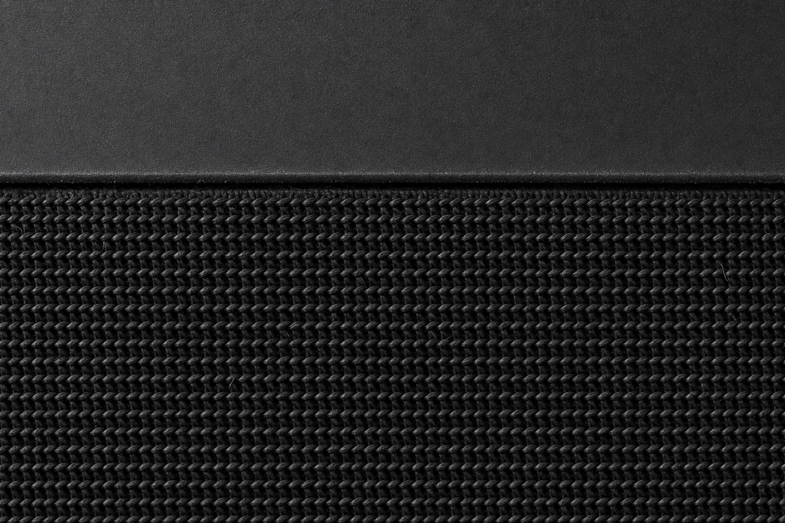 Close-up of Station’s acoustic knit texture and its seam with the matte charcoal shell.
